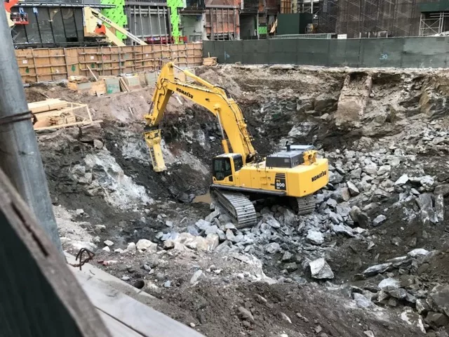 Excavation work using a large excavator using a hammer attachment to break apart rock or concrete